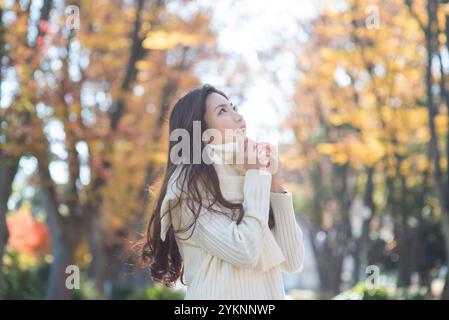 Femme dans la vingtaine regardant les feuilles d'automne Banque D'Images