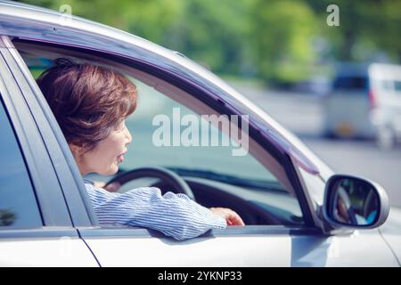 Femme âgée assise sur le siège du conducteur Banque D'Images