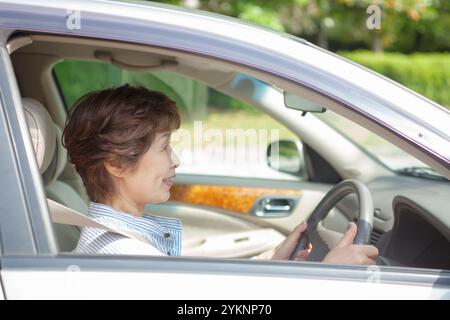 Femme âgée assise sur le siège du conducteur Banque D'Images