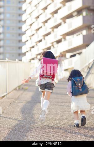 Les enfants des écoles primaires et les sœurs de maternelle courent sur la route Banque D'Images