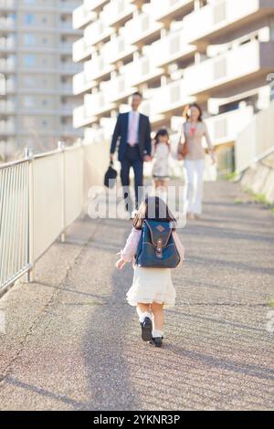 Fille de maternelle courant vers la famille Banque D'Images