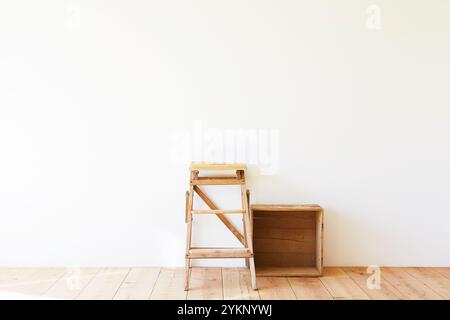 Plancher en bois, mur blanc, boîte à vin et escabeau Banque D'Images