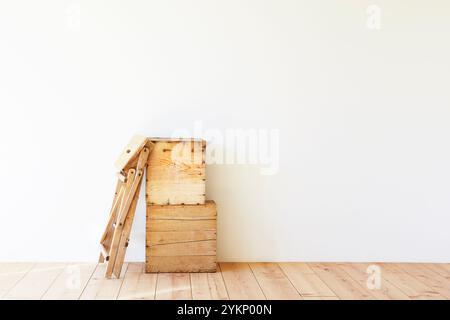 Plancher en bois, mur blanc, boîte à vin et escabeau Banque D'Images