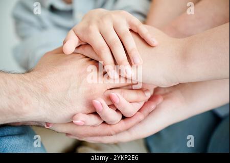 Famille mignonne mettant les mains empilées ensemble promettant aide et soutien les uns aux autres. Vue rapprochée des membres de la famille qui se tiennent la main de manière à soutenir. Concept d'unité, travail d'équipe, soutien mutuel. Banque D'Images