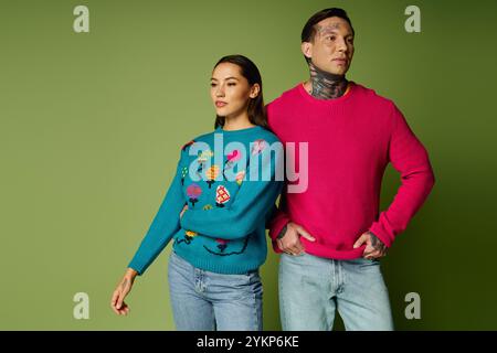 Un jeune couple élégant présente des chandails uniques tout en se tenant en toute confiance dans un cadre animé. Banque D'Images