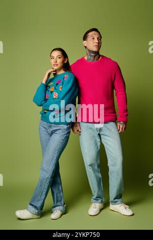 Un jeune couple tendance présente leur mode hivernale coordonnée avec des couleurs et des styles ludiques. Banque D'Images