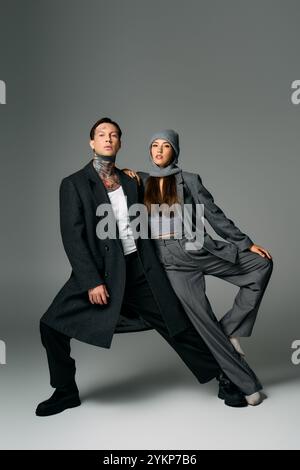 Un jeune couple met en valeur la mode moderne avec confiance et créativité dans une pose dynamique. Banque D'Images