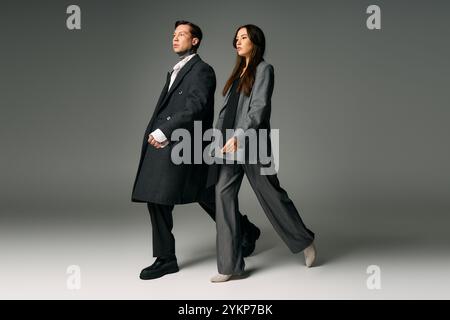 Un jeune couple met en valeur la mode contemporaine tout en marchant ensemble dans un cadre de studio. Banque D'Images