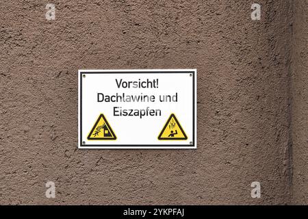 Augsbourg, Bavière, Allemagne - 18 novembre 2024 : panneau d'avertissement sur un mur de maison : méfiez-vous des avalanches de toit et des glaçons qui tombent. Avis du propriétaire sur les dangers hivernaux *** Warnschild an einer Hauswand : Vorsicht vor Dachlawinen und herabfallenden Eiszapfen. Hinweis vom Eigentümer auf winterliche Gefahren Banque D'Images