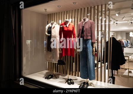 Mannequins féminins dans l'affichage de la fenêtre en verre de magasin habillé automne décontracté - vêtements élégants d'hiver, scène de nuit. Banque D'Images