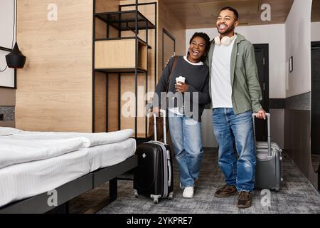 Un jeune couple embrasse le bonheur en déballant ses valises dans une chambre d’hôtel élégante pendant ses vacances. Banque D'Images