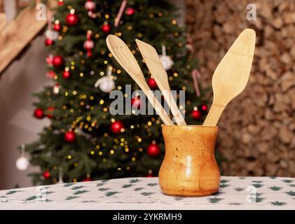 Ustensiles de cuisine en bois sur table, arbre de Noël sur fond. Banque D'Images