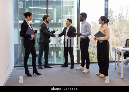 Divers professionnels du bureau moderne s'engagent dans la poignée de main, représentant le travail d'équipe, la collaboration et la dynamique de réunion d'entreprise. Banque D'Images