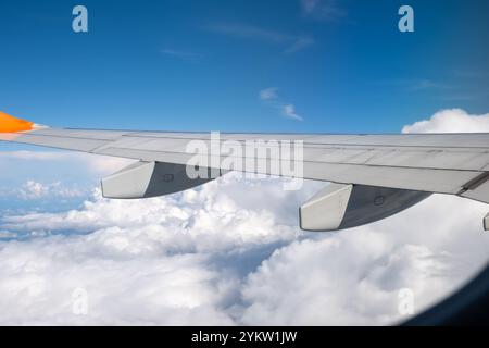 Vue depuis la fenêtre de l'avion sur l'aile et le paysage avec des nuages. Banque D'Images