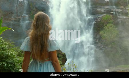 Jeune femme avec de longs cheveux blonds en robe bleu clair se tient devant Banque D'Images