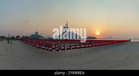 Une photo de nombreux drapeaux des Émirats arabes Unis sur la plage publique de Jumeirah, avec le Jumeirah Marsa Al Arab Hotel et le Burj Al Arab Hotel dans les Far Banque D'Images