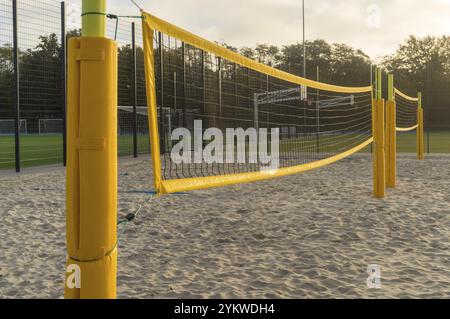 Filet de volley jaune s'étendant sur un terrain de Beach volley de sable par une journée ensoleillée Banque D'Images