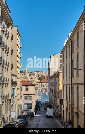 Marseille. France - 19 novembre 2024 : une rue animée à Marseille menant au port, présentant des bâtiments historiques, une activité animée, et Banque D'Images