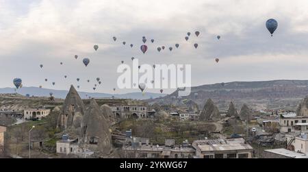 Une photo de montgolfières survolant le parc national historique de Goreme et la ville de Goreme au lever du soleil Banque D'Images