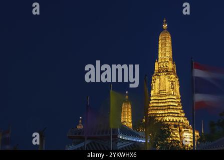Une photo du prang central du temple Wat Arun, la nuit, derrière des drapeaux agités Banque D'Images