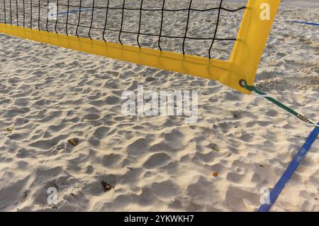 Filet de volley jaune jetant une ombre sur le sable d'un terrain de volley-ball de plage vide Banque D'Images