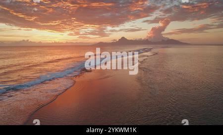 Plage de l'île tropicale au lever du soleil, belle couleur lumineuse coucher de soleil de mer, vagues doucement roulant côte, ciel et eau dans des tons vibrants d'orange et de rose. Paradis de la nature, fond de voyage d'été Banque D'Images