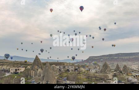 Une photo de montgolfières survolant le parc national historique de Goreme et la ville de Goreme au lever du soleil Banque D'Images