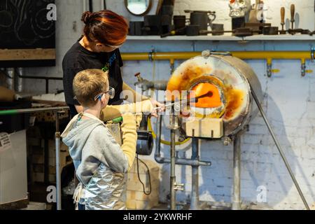 Garçon avec instructeur à l'atelier de verrerie The Forge, Hainault Forest Visitor Centre, Hainault, Londres, Angleterre Banque D'Images