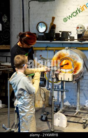 Garçon avec instructeur à l'atelier de verrerie The Forge, Hainault Forest Visitor Centre, Hainault, Londres, Angleterre Banque D'Images