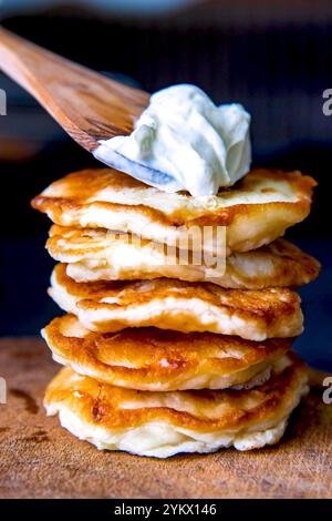 Crêpes sur une planche de bois avec de la crème sure. Banque D'Images