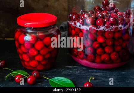 Conserves de cerises faites maison dans un bocal en verre et cerises rouges fraîchement dénoyautées conservées dans du sirop de sucre. Nourriture biologique en conserve du jardin. Banque D'Images