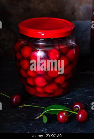 Conserves de cerises faites maison. Cerises fraîches dénoyautées dans du sirop de sucre dans un bocal en verre. Nourriture biologique en conserve du jardin. Banque D'Images