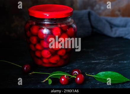 Conserves de cerises faites maison. Cerises fraîches dénoyautées dans du sirop de sucre dans un bocal en verre. Nourriture biologique en conserve du jardin. Banque D'Images