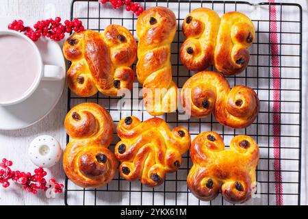 Pains suédois au safran traditionnels lussekatt de différentes formes, servis avec du cacao sur une table en bois. Petits pains pour : Lucia's Day. Style rustique, sélectif Banque D'Images