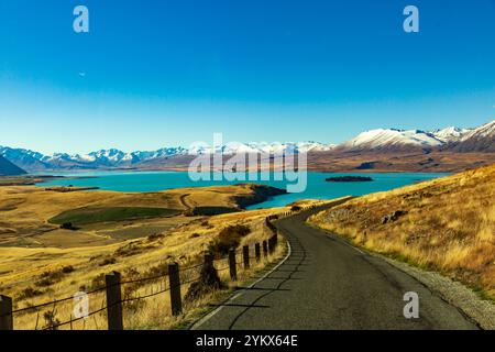 Une vue imprenable sur la route sinueuse menant au lac Tekapo, en Nouvelle-Zélande, prise par une journée ensoleillée. Les eaux bleu turquoise du lac scintillent sous le Banque D'Images