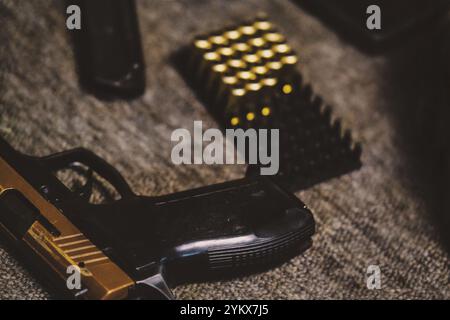 Arme de poing avec des munitions organisées soigneusement sur le plateau, éléments de fond sombre améliorant l'atmosphère Banque D'Images