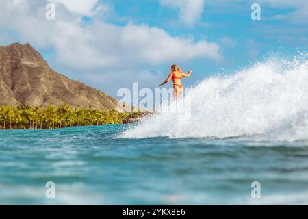 Surfeur chevauche gracieusement une vague avec l'emblématique Diamond Head en arrière-plan par une journée ensoleillée. Banque D'Images