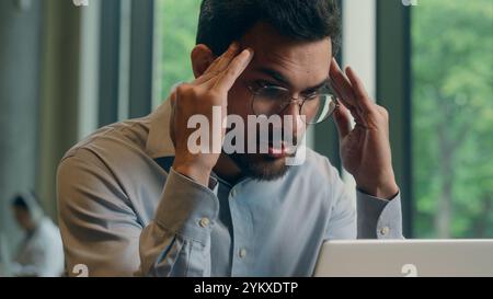 Homme d'affaires indien homme d'affaires homme arabe fatigué travailleur d'affaires épuisé travailleur indépendant en ligne ordinateur portable de travail dans le café stress santé mal de tête triste bouleversement Banque D'Images