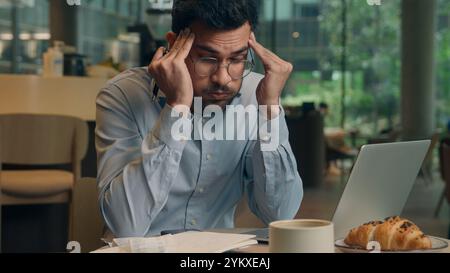 Homme d'affaires bouleversé problème de paperasse Indien Arabique homme d'affaires visiteur dans le café homme triste frustré gars anxieux travail indépendant ordinateur portable fatigué stress Banque D'Images