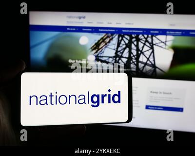 Dans cette illustration photo, une personne tient un smartphone avec le logo de la société de services publics britannique National Grid plc en face du site Web. Banque D'Images