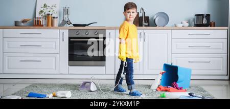 Petit garçon jouant avec les fournitures de nettoyage et le fer à repasser à la maison. Enfant en danger Banque D'Images