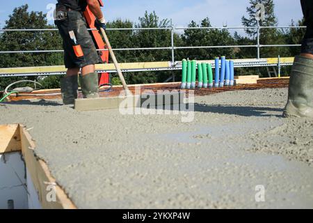 Ouvriers remplissant le sol du deuxième étage avec le béton, le noyau et le bâtiment de construction de coquille Banque D'Images