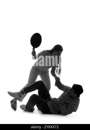 Silhouette de femme avec poêle à frire battant l'homme sur fond blanc. Concept de violence domestique Banque D'Images