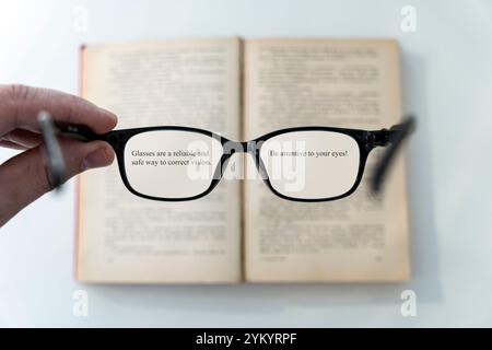 livre et lunettes pour lire et écrire sur un arrière-plan flou avec espace de copie, mise au point sélective. lecture de lunettes dans ses mains sur un livre flou backgr Banque D'Images