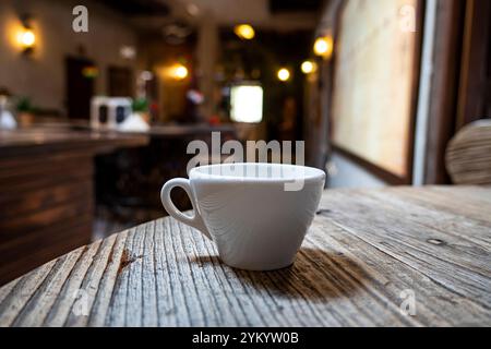 Café latte chaud dans la tasse blanche sur la table dans le restaurant et le café. Tasse de café chaude sur la table en bois dans le fond flou du café-restaurant. Banque D'Images