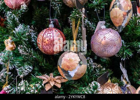 Jouet d'arbre de Noël accroché à la branche de sapin neigeux vert. Vue rapprochée de la branche d'arbre de Noël avec des boules décoratives, des jouets et une guirlande brillante. Christma Banque D'Images