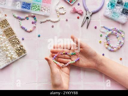 Enfant créant des bijoux faits à la main, profitant d'un passe-temps relaxant Banque D'Images