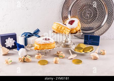 Beignets festifs sur un plateau d'argent parmi les boîtes avec des cadeaux pour les vacances Hanukkah. dreidels tétraédriques en bois. Le concept de Hanukkah Banque D'Images