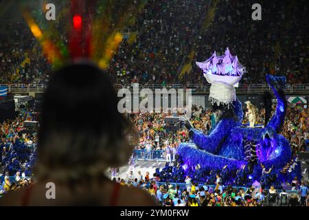 Rio de Janeiro, RJ, Brésil. 13 février 2024. Un spectateur regarde l'école de samba Portela passer des gradins populaires, offrant les places les moins chères du Sambadrome, à Rio de Janeiro, au Brésil. Les écoles de Samba les plus prétentieuses ont défilé le 12 février. Organisé chaque année, le Carnaval de Rio de Janeiro, au Brésil, est considéré comme le plus grand du monde, avec environ deux millions de personnes dans les rues chaque jour. Le défilé officiel du carnaval dans le sambodrome de Rio de Janeiro en 2024 a rendu hommage aux peuples indigènes et à la culture afro-brésilienne avec des chars évoquant l'héritage esclavagiste du Brésil. (Credi Banque D'Images