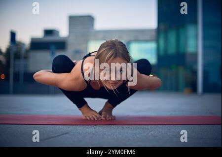 Praticien de yoga démontre la pose avancée sur tapis dans la zone urbaine pendant les heures de crépuscule Banque D'Images